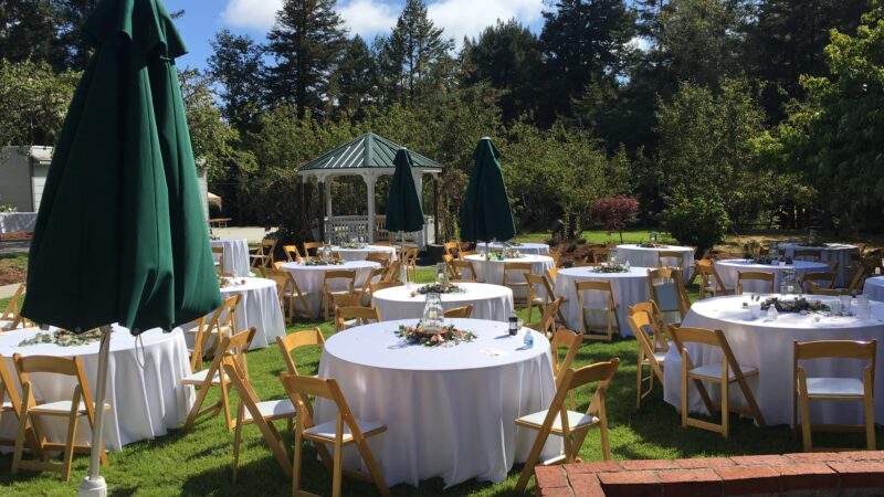 Wedding tables set on the main lawn at Mitchell Grove, surrounded by gardens, orchards, and redwoods in Humboldt County