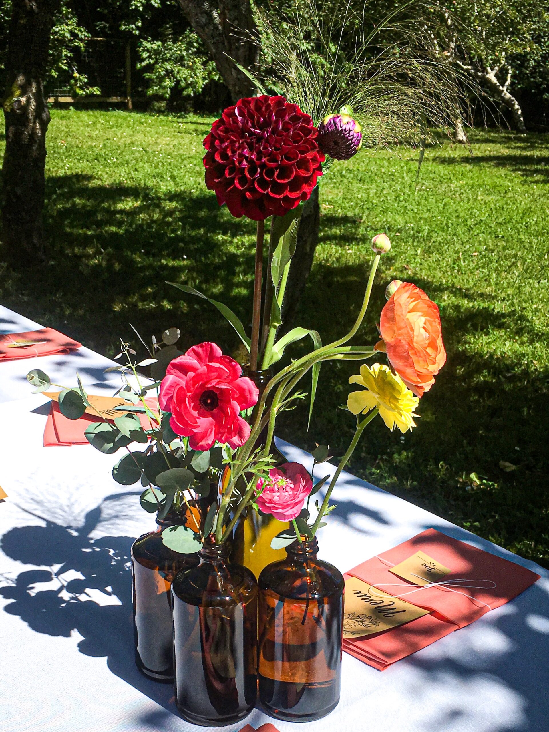 Kombucha bottles repurposed as DIY wedding vases with fresh flowers at Mitchell Grove