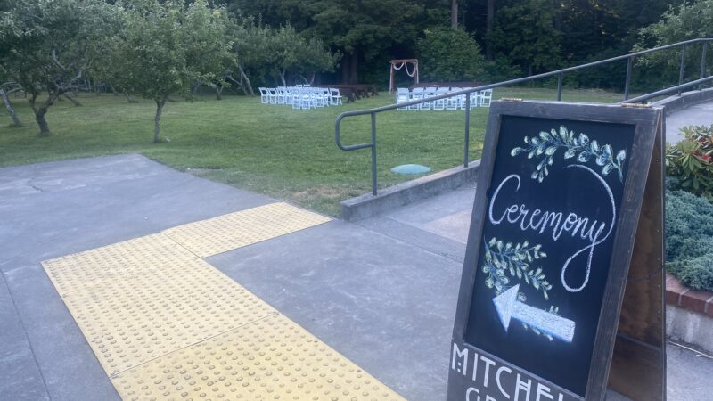 Rustic chalkboard wedding sign at Mitchell Grove, pointing toward the redwood ceremony area beside the apple orchard