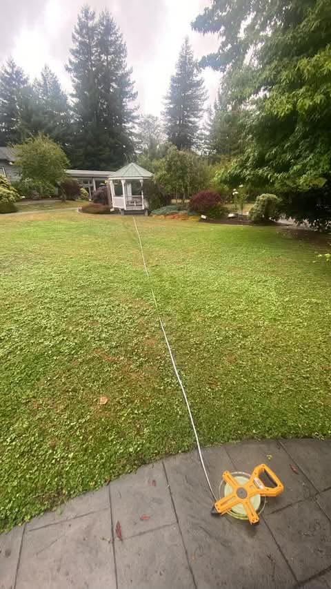 Yellow measuring tape marking the 53-foot-6-inch wedding aisle from the gazebo to the garden arch at Mitchell Grove.