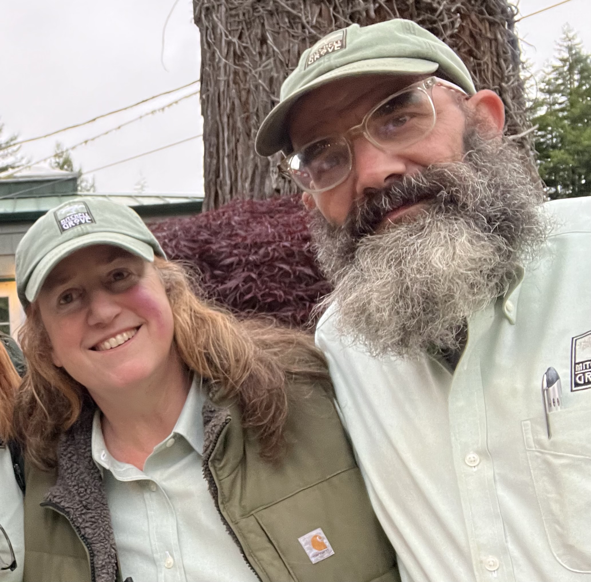 Owners Will and Julie standing in front of a tree at Mitchell Grove wedding venue, welcoming couples with a relaxed, down-to-earth vibe.